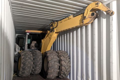 Backhoe loaded into shipping container.