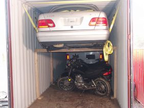 Car and motorcycles in shipping container.
