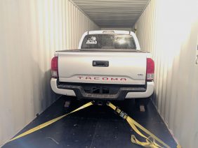 Pickup truck secured to shipping container.